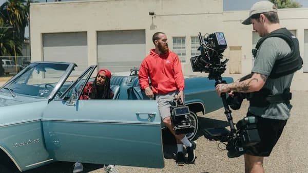 man in red dress shirt and black pants standing beside white car during daytime
