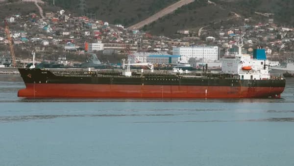 A large oil tanker floats near a city.