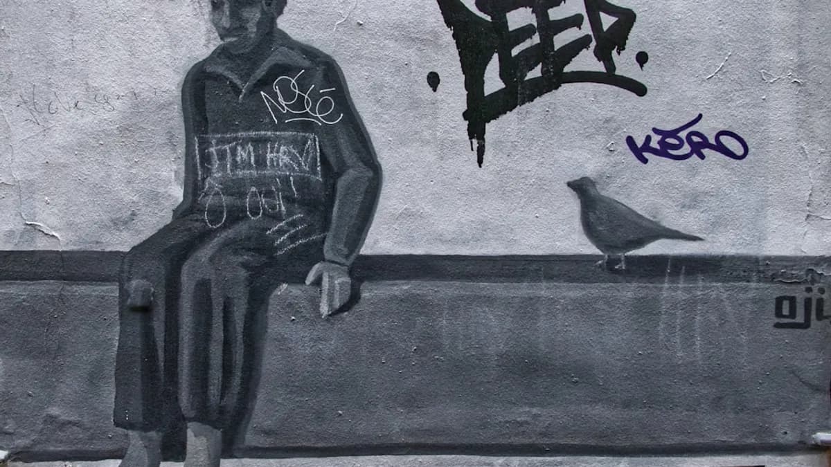 man in black and white tank top and pants standing beside wall with graffiti