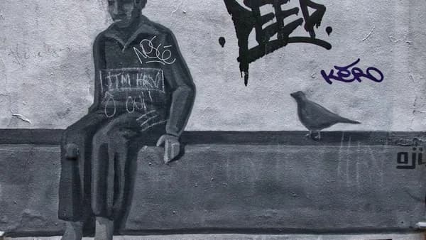 man in black and white tank top and pants standing beside wall with graffiti