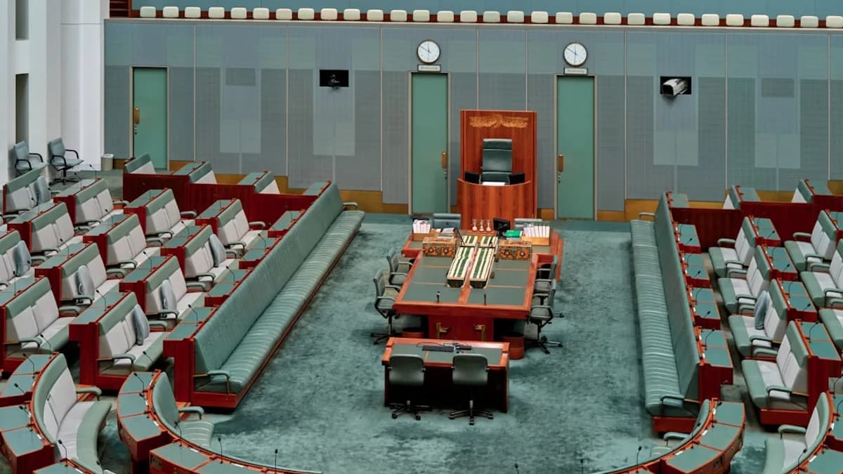 Empty parliamentary chamber with rows of seats.