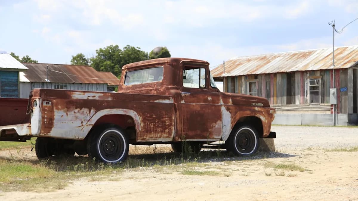 an old rusted truck is parked in a field