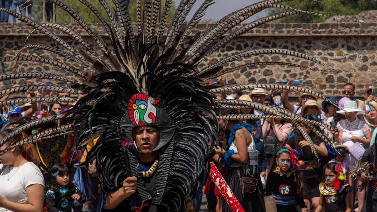 a man in a feathered headdress walking in front of a crowd