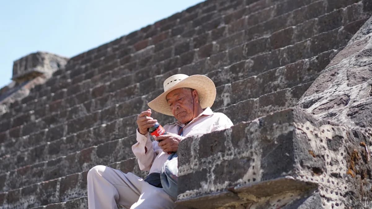 man sitting on concrete stair holding soda bottle