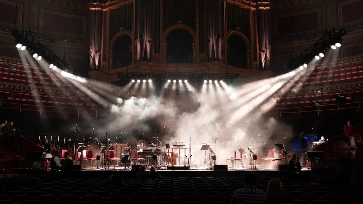 Orchestra performing on a stage with dramatic lighting.