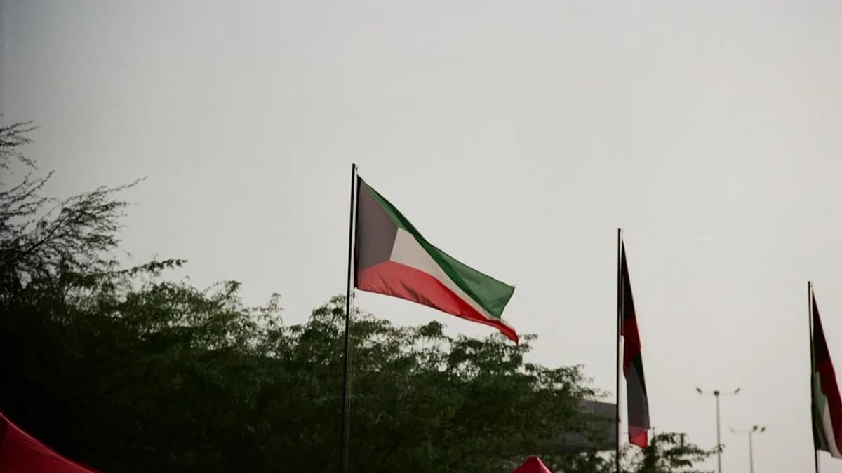 Kuwaiti flag waving against a cloudy sky