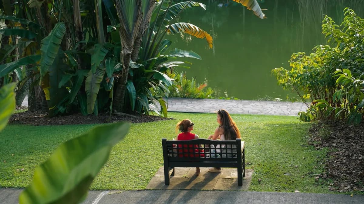 Two people sitting on a bench by a lake.