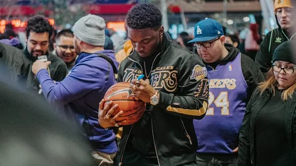 man in blue and yellow jacket holding brown football