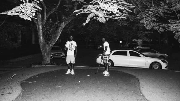 a couple of men standing next to a white car