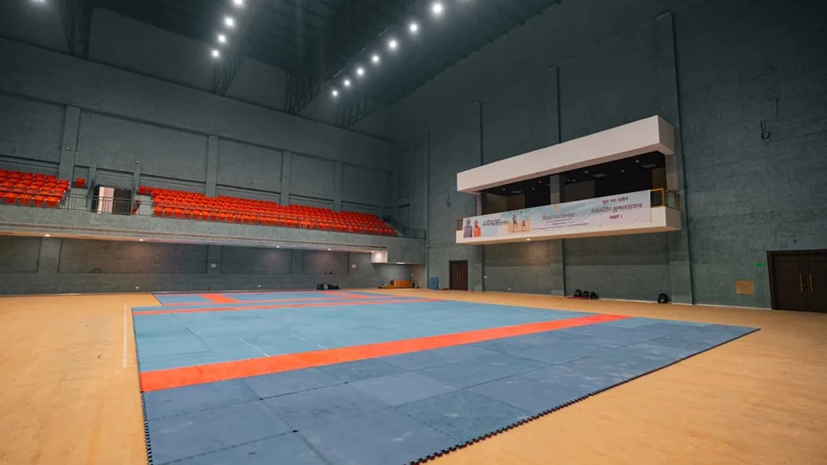 Indoor stadium with a blue and orange wrestling mat.
