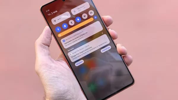 A hand holds a smartphone showing notifications.