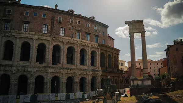 Ancient roman ruins stand under a sunny sky.