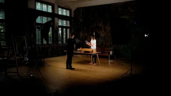 Two people in a dimly lit room with studio lighting.