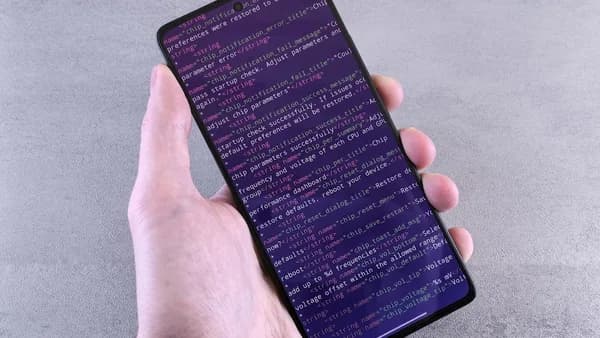 Hand holding smartphone displaying lines of code