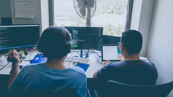 two men using computer and laptop