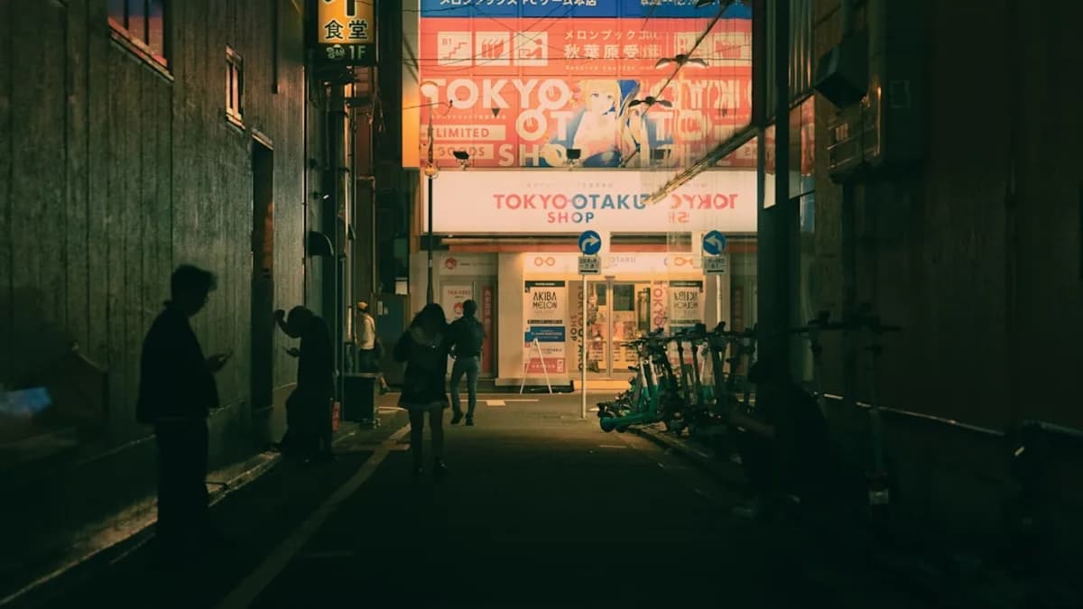 People walking down a dark alley with bright signs.