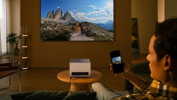 Man uses projector to display mountain landscape on wall.