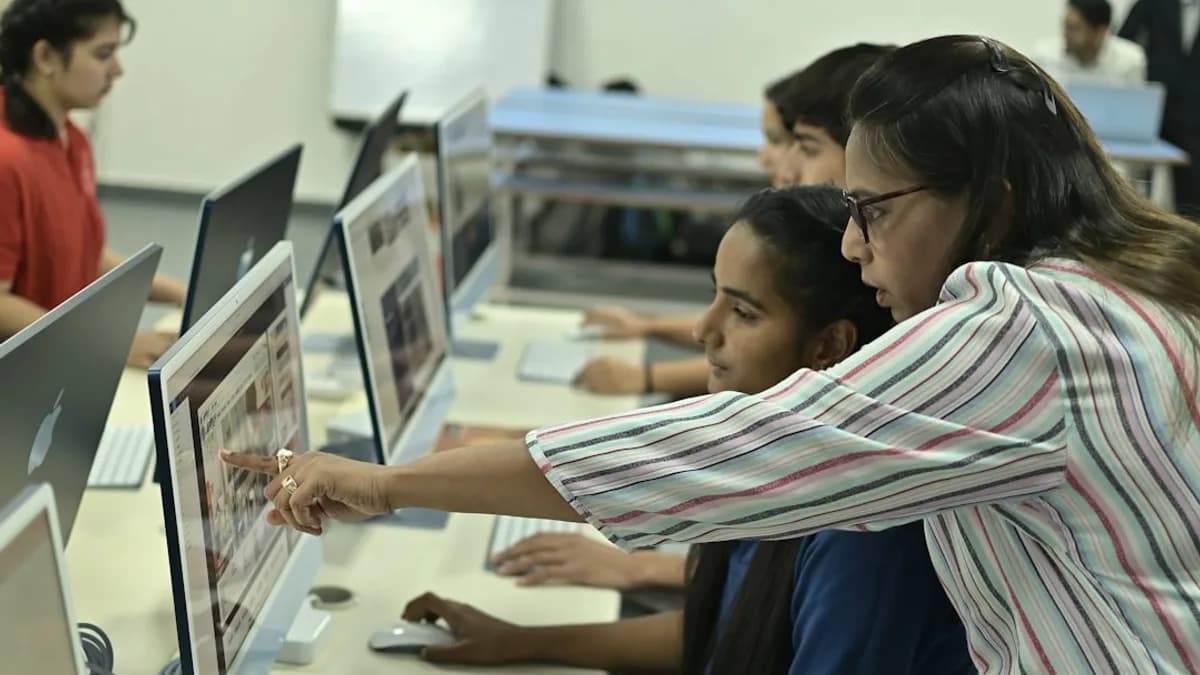 Teacher guiding students on computer in classroom.