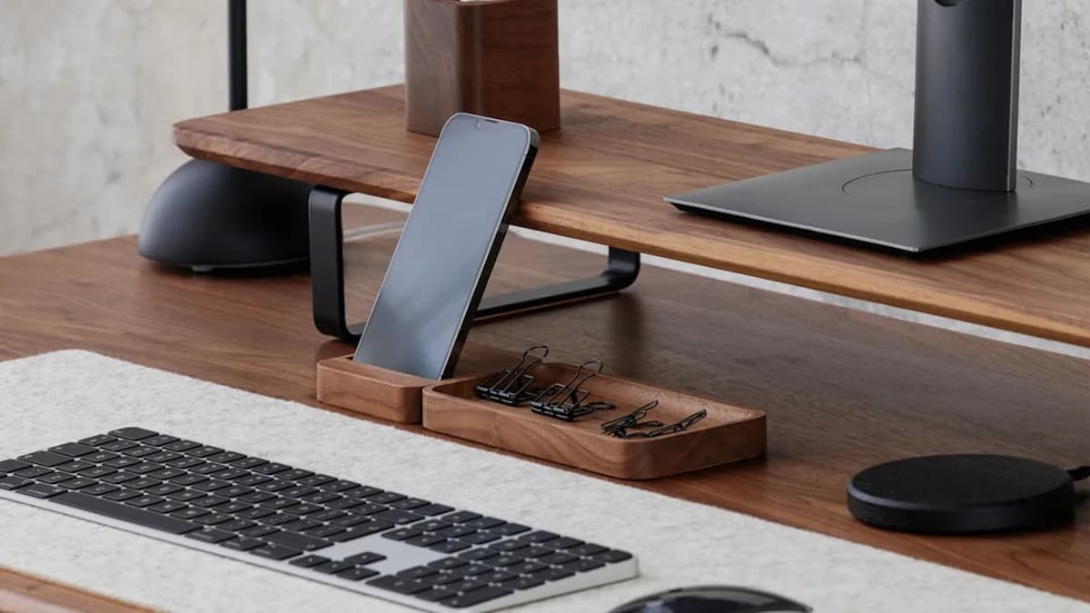 a computer desk with a keyboard, mouse and cell phone