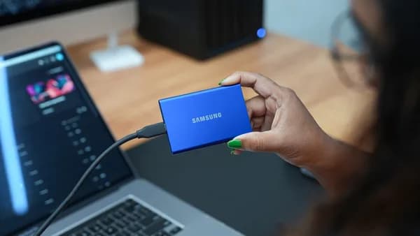 A woman holding a blue samsung power bank in front of a laptop