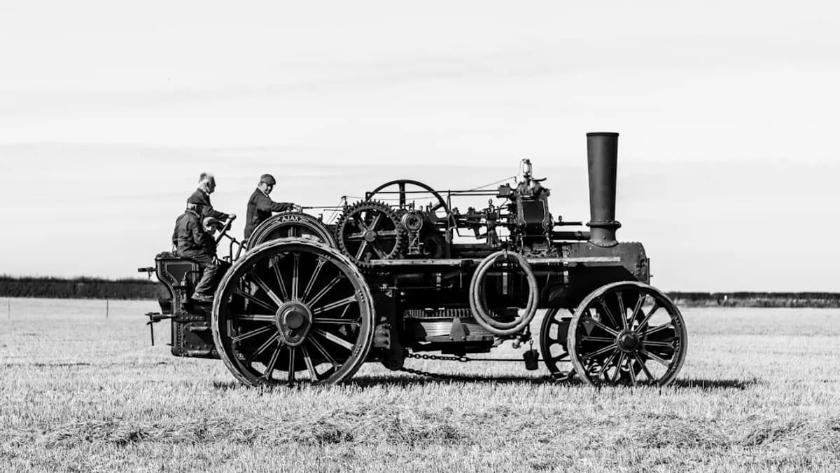 a black and white photo of a man driving a tractor