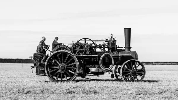 a black and white photo of a man driving a tractor