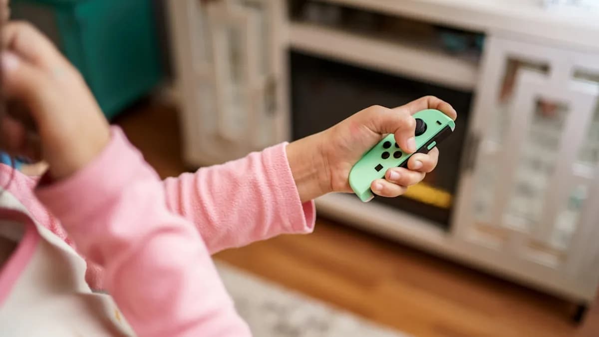 child in pink long sleeve shirt holding green and white plastic toy