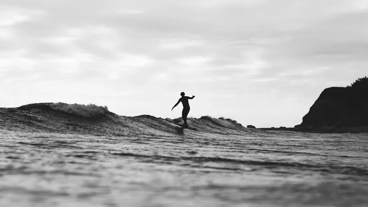 grayscale photography of person surfing on sea