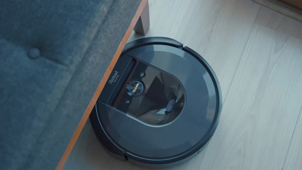 a robotic vacuum is on the floor next to a couch