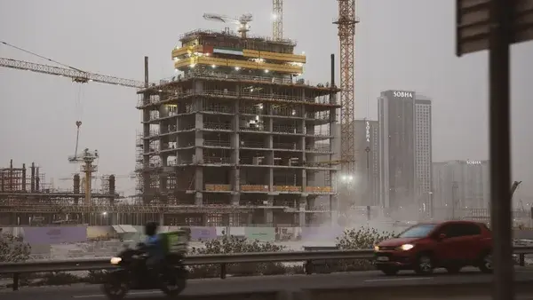 Construction site with cranes and unfinished building.