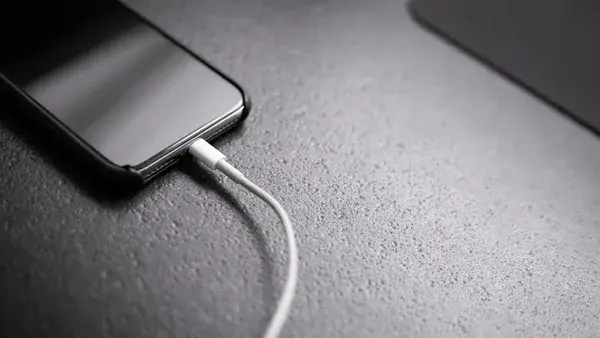 black smartphone with charger cord connected