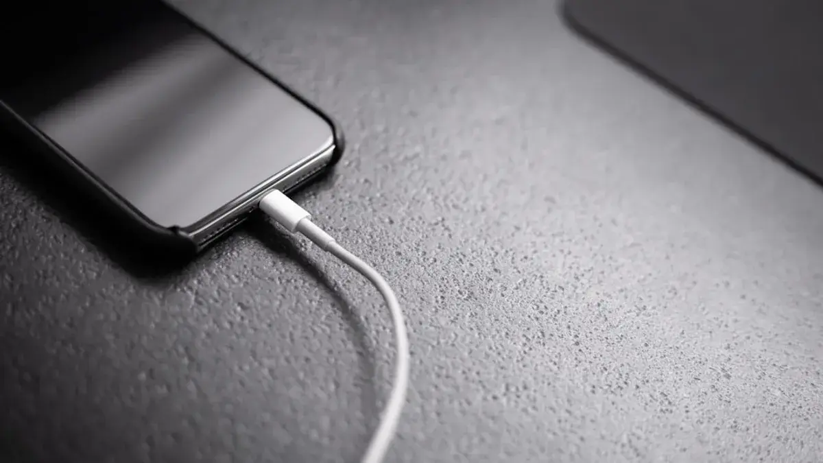 black smartphone with charger cord connected